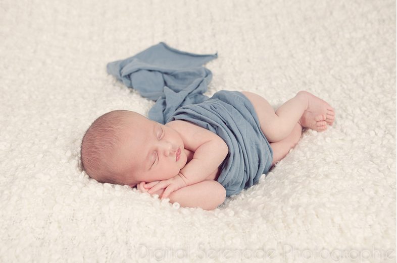 Nouveau-né endormi dans un lange bleu, séance naissance à domicile